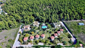 An aerial view of a residential area with houses arranged in a grid pattern, surrounded by dense forest. - Sani Polyastron Hotel & Spa (Kassandra)