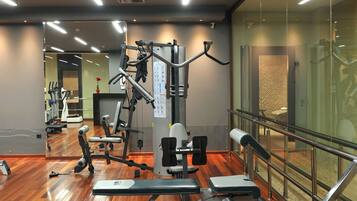 A gym with exercise equipment, wooden flooring, and a glass wall.