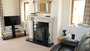 A living room with a fireplace, a television, a sofa, and a coffee table. - Quay Rest  (Rooskey)