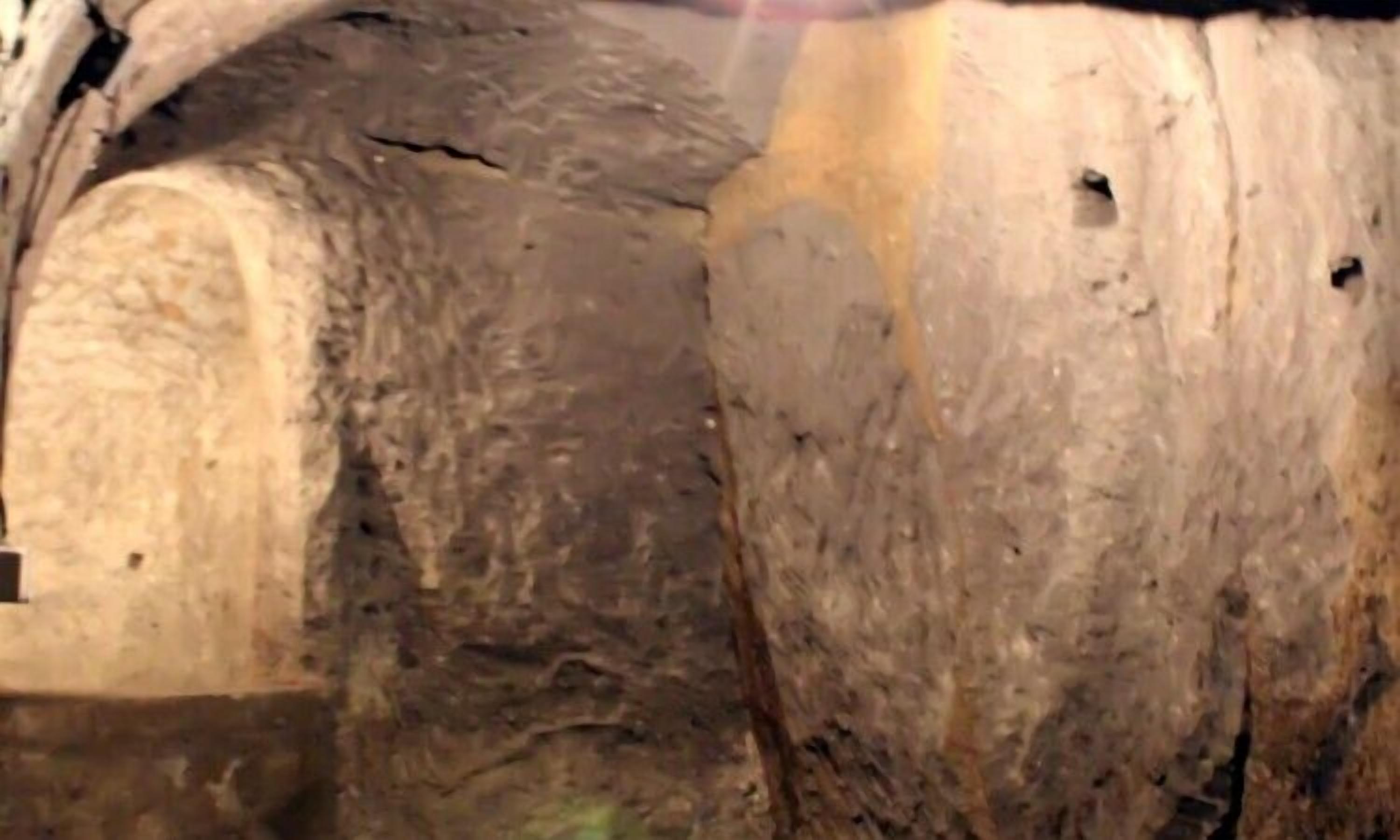 Eine raue, strukturierte Wand mit einer großen, unebenen Oberfläche und einigen kleinen Löchern.