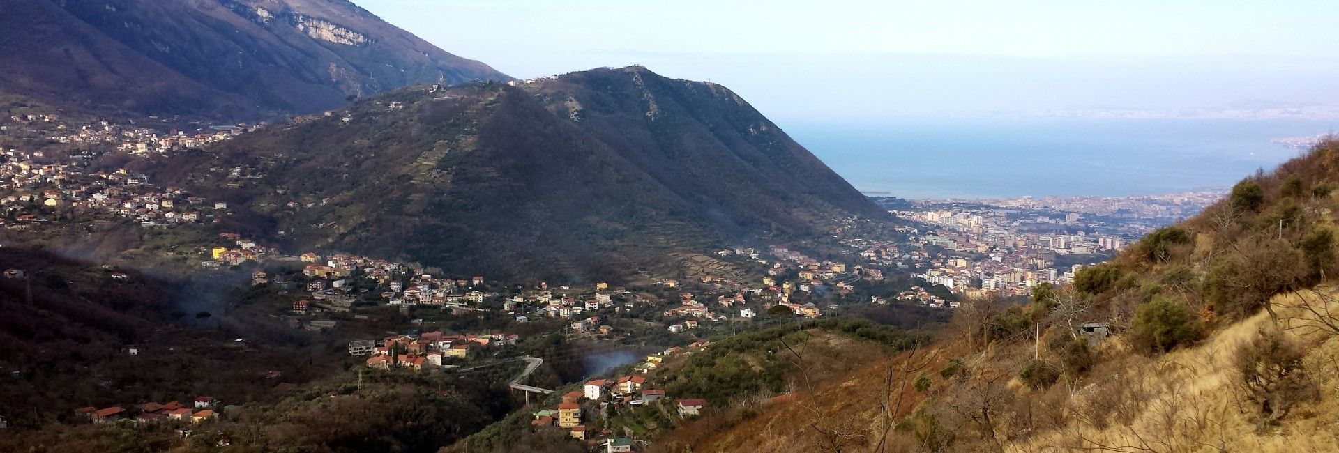 A mountainous landscape with a town nestled at its base, overlooking a body of water.