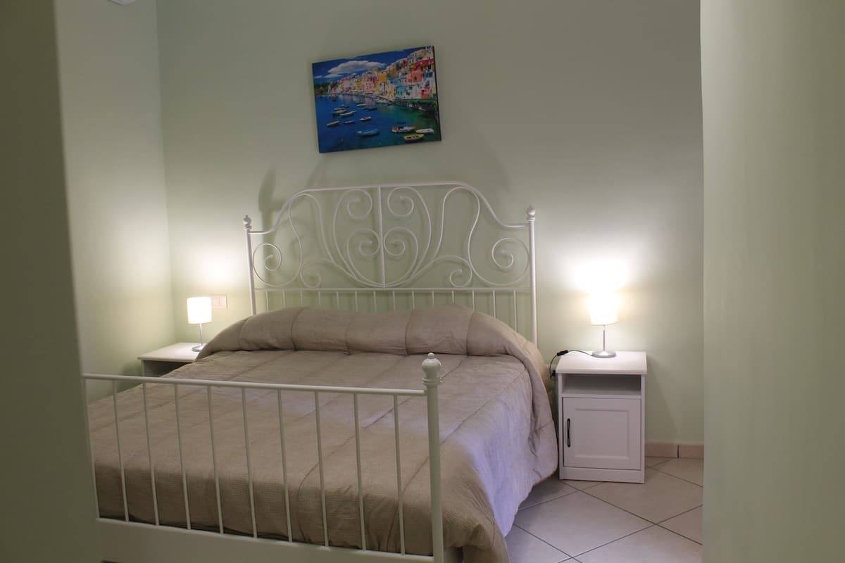 Une chambre à coucher avec un lit, deux tables de chevet et un tableau accroché au mur.