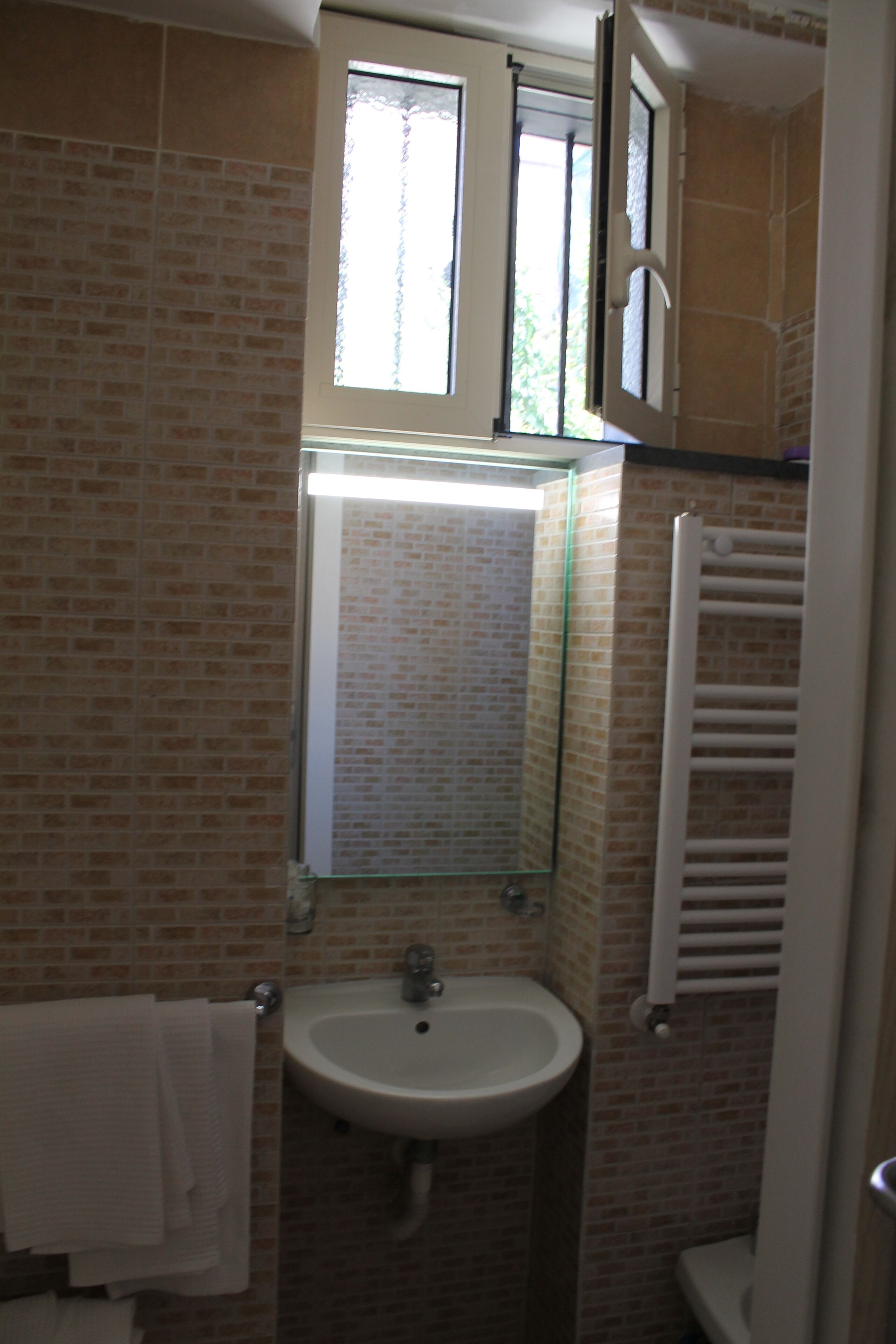 Une salle de bain équipée d’un lavabo, d’un miroir et d’un porte-serviettes.