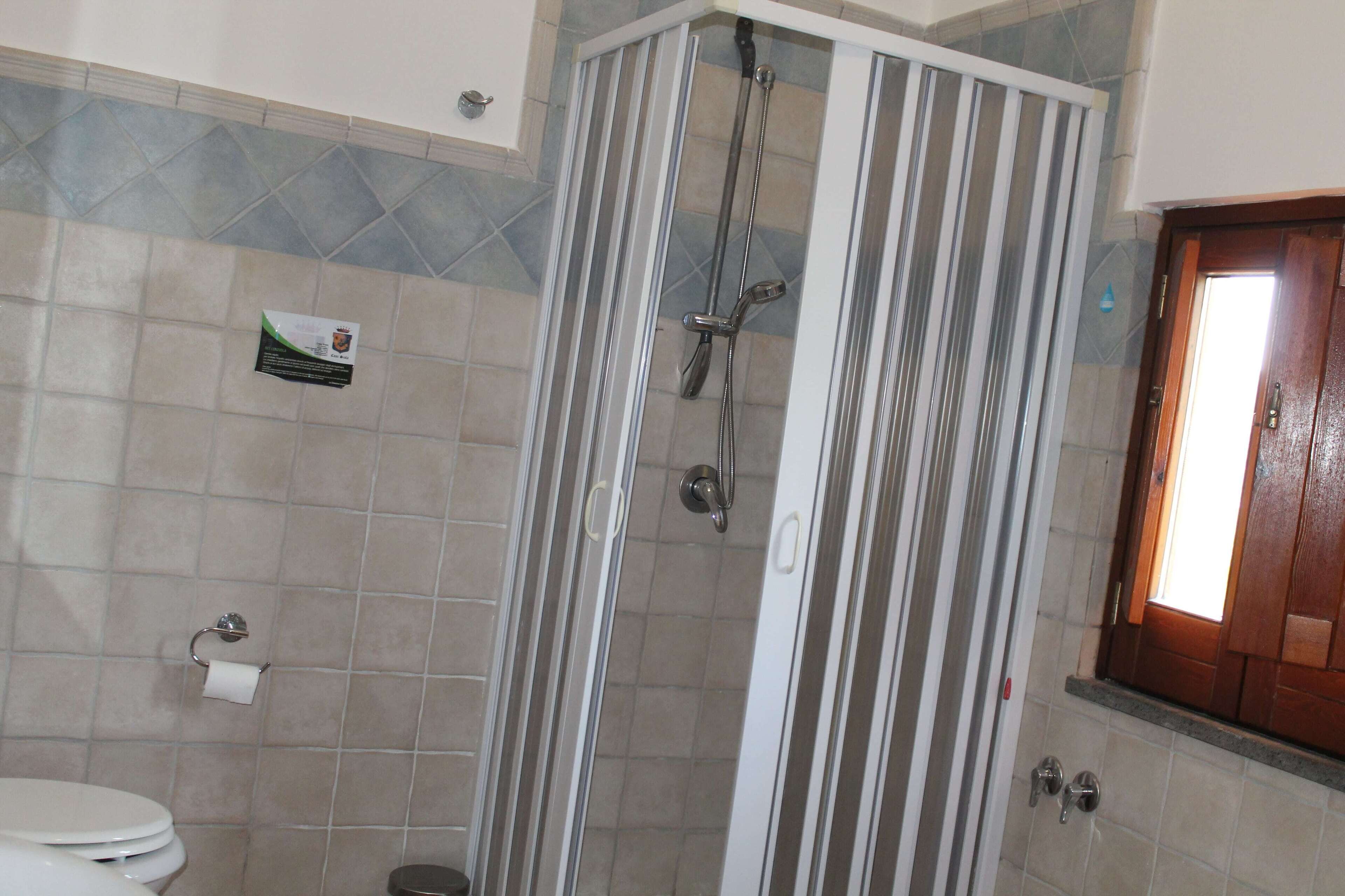 A bathroom with a shower, toilet, and a towel rack.