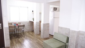 A compact living space with a kitchenette, a dining area, and a green sofa. - Beit Alfa Kibbutz Country Lodging (Gilboa)