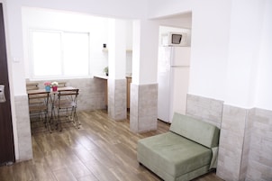 Um espaço compacto com cozinha compacta, área de refeições e sofá verde.