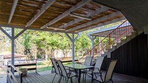 An outdoor patio with a table and chairs, a staircase, and a view of the surrounding greenery. - Beit Alfa Kibbutz Country Lodging (Gilboa)