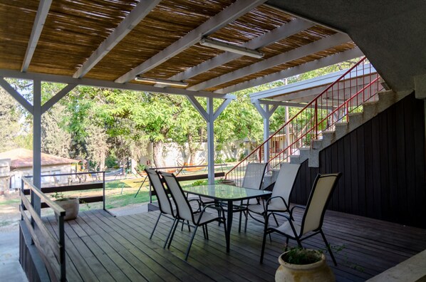 An outdoor patio with a table and chairs, a staircase, and a view of the surrounding greenery.
