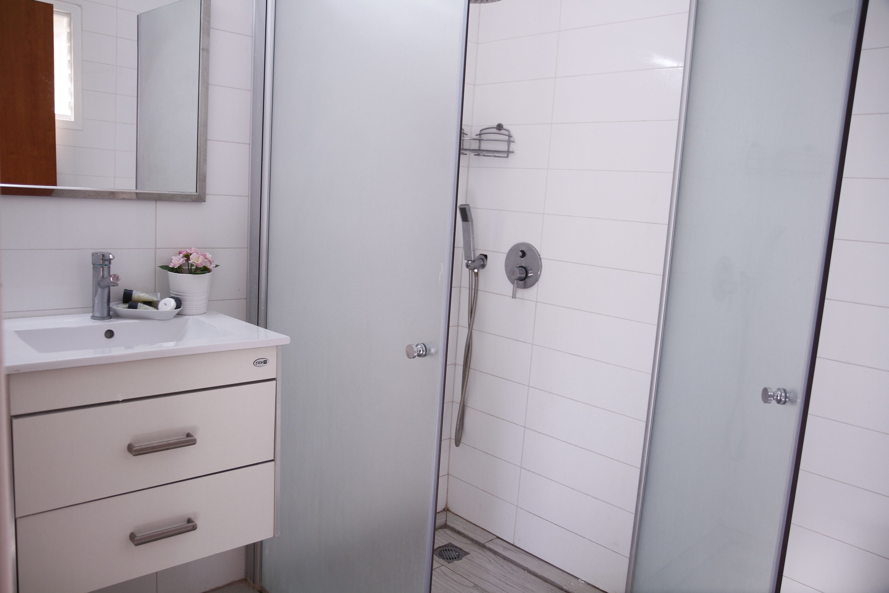 A bathroom with a white sink, mirror, and a glass shower enclosure.