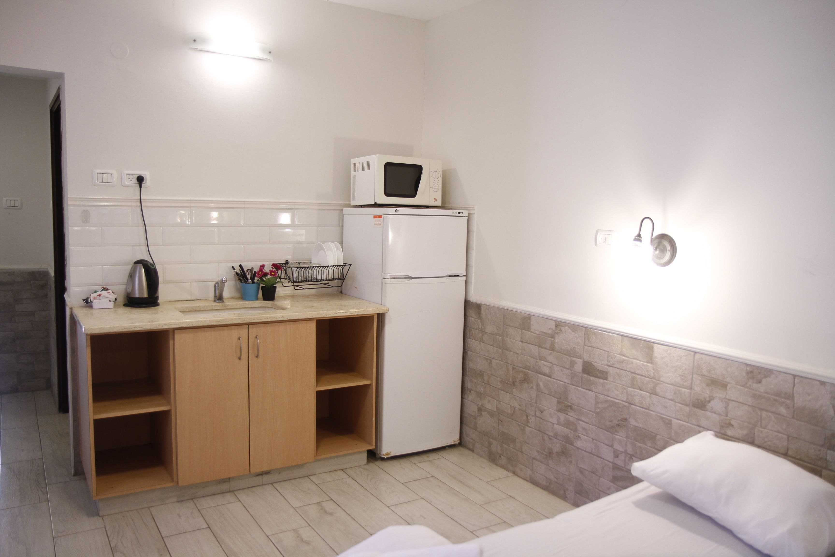 A compact kitchen with a microwave, refrigerator, and wooden cabinets.