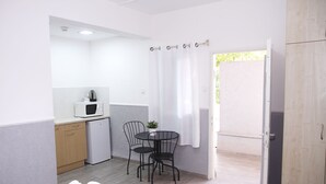 A compact room with a kitchenette, a dining area with two chairs, a small table, and a bed. - Beit Alfa Kibbutz Country Lodging (Gilboa)