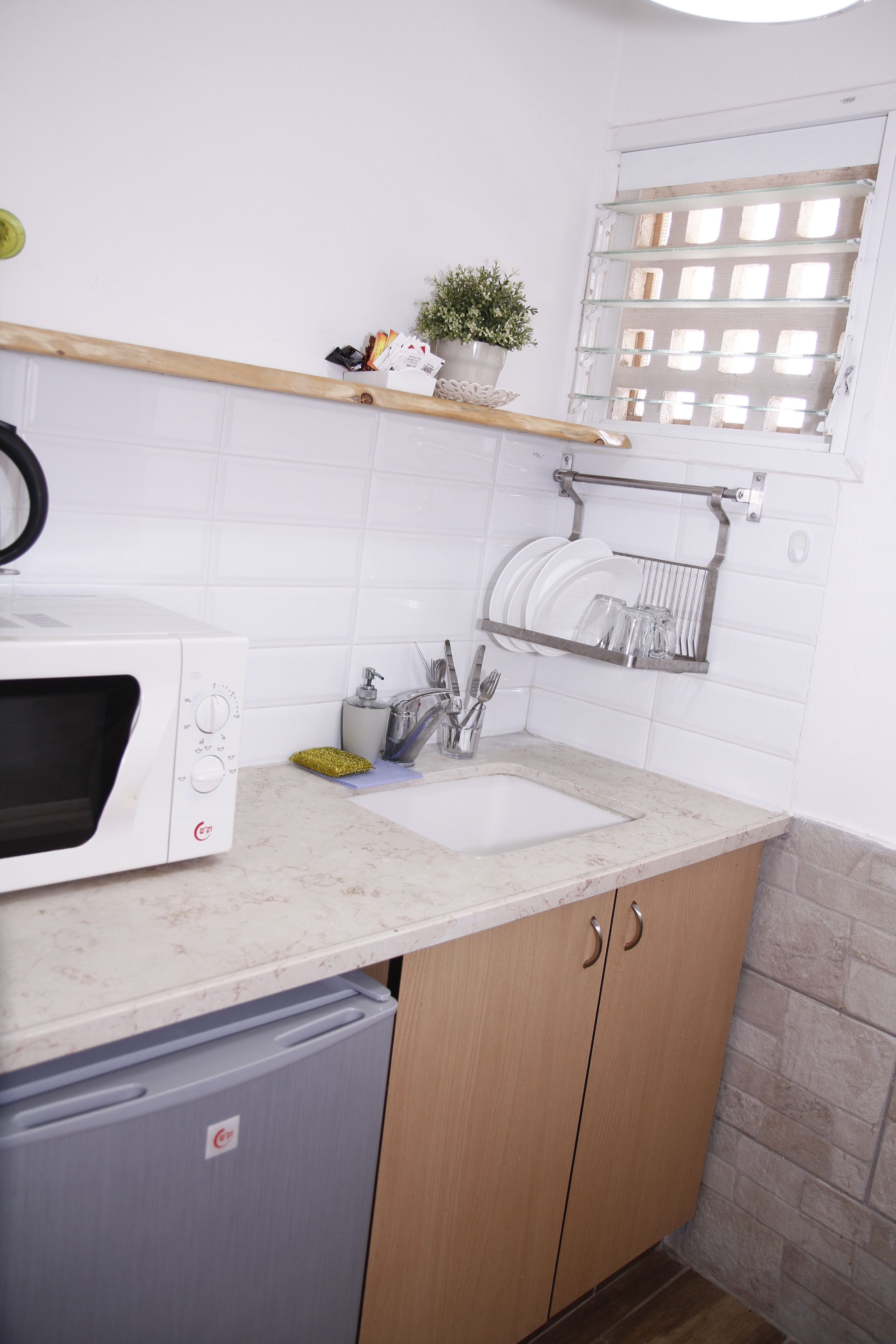 Una cucina compatta con forno a microonde, lavello e mobili in legno.