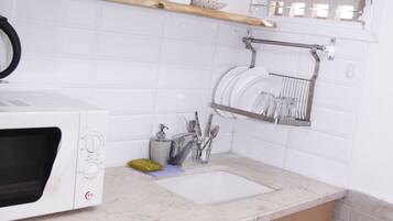 Una cucina compatta con forno a microonde, lavello e mobili in legno.