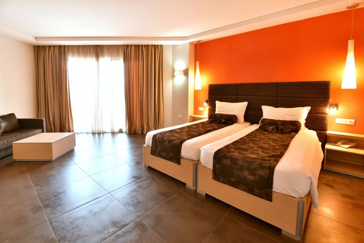 A modern hotel room with a large bed, a sofa, and a desk.