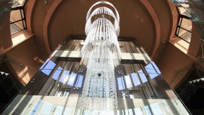 A large, ornate chandelier in a spacious atrium with high ceilings and large windows allowing natural light to enter. - LTI Dolce Vita Sunshine Resort (Golden Sands)