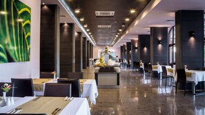 A modern restaurant with a long dining area, high ceilings, and a central decorative piece.