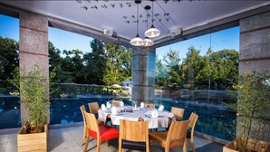 An outdoor dining area with a pool view, wooden chairs, and a table set for dining. - LTI Dolce Vita Sunshine Resort (Golden Sands)