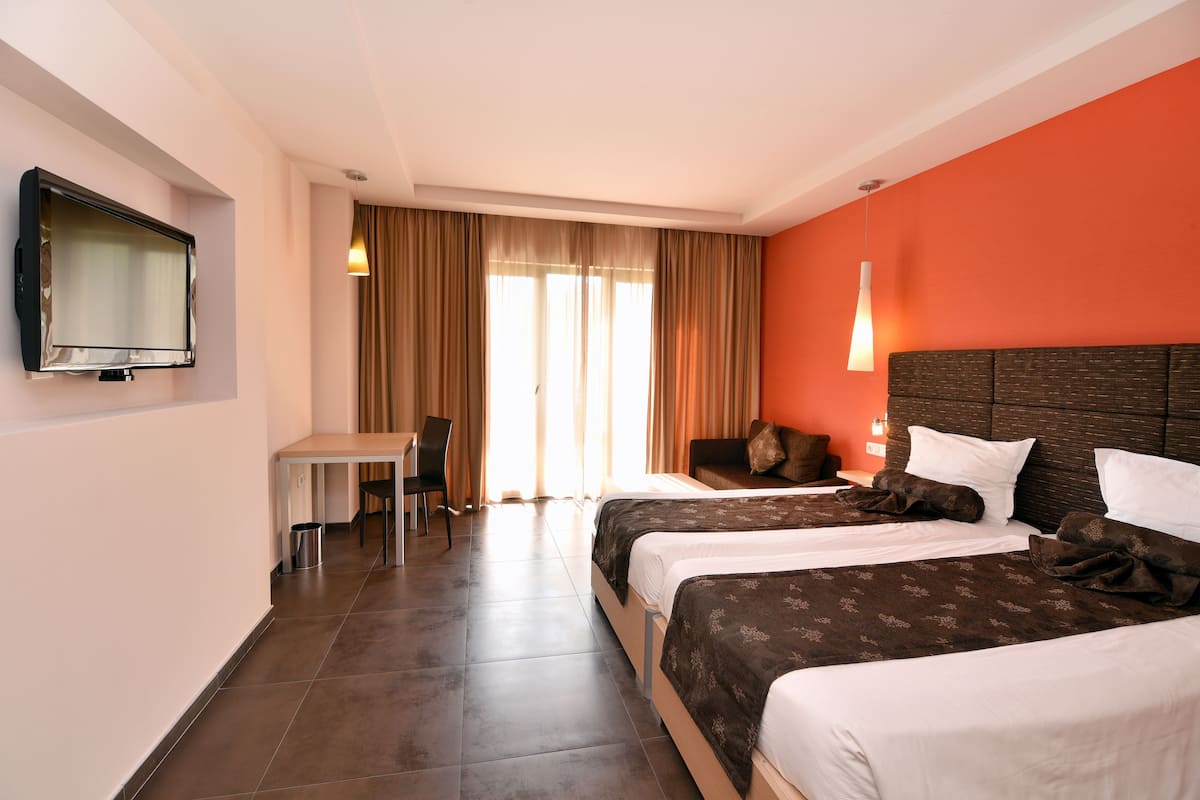 A hotel room with two beds, a TV, a desk, and a chair.