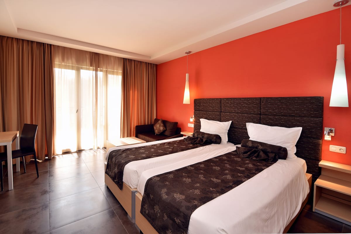A hotel room with two beds, a desk, and a chair.