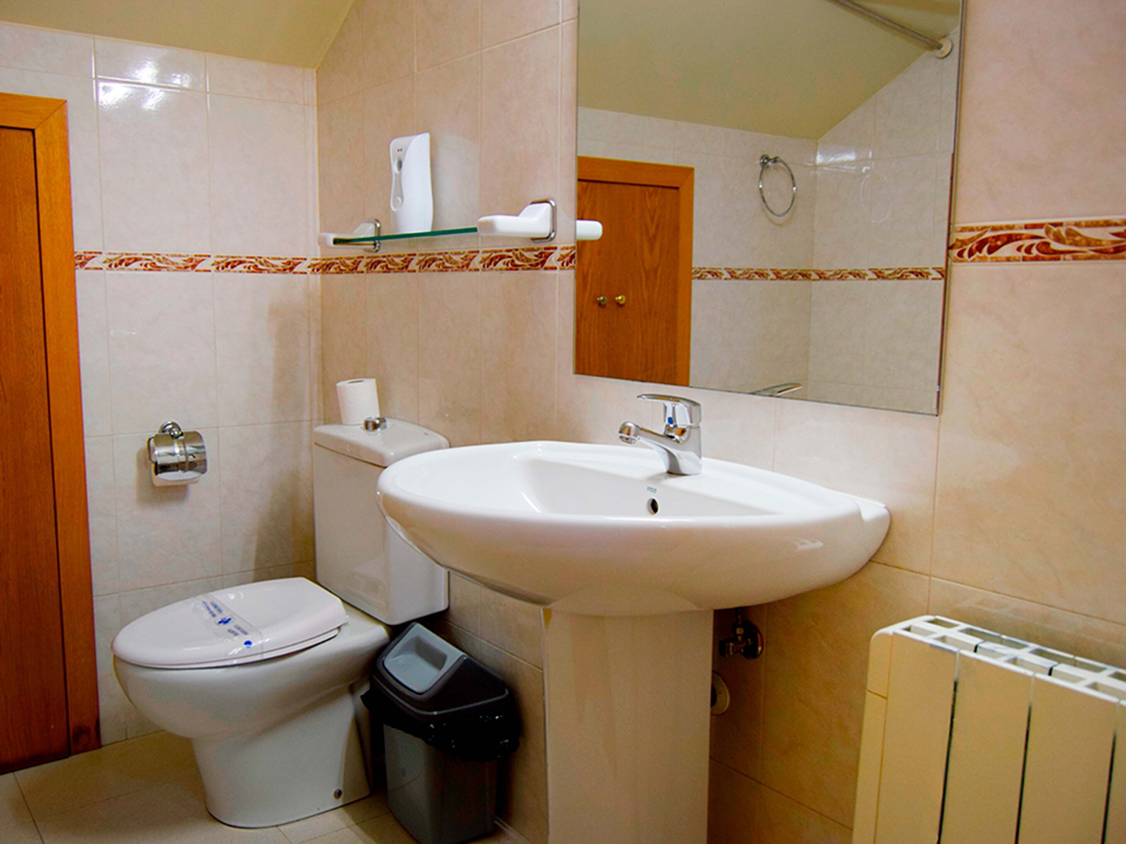 A bathroom with a toilet, sink, and mirror.