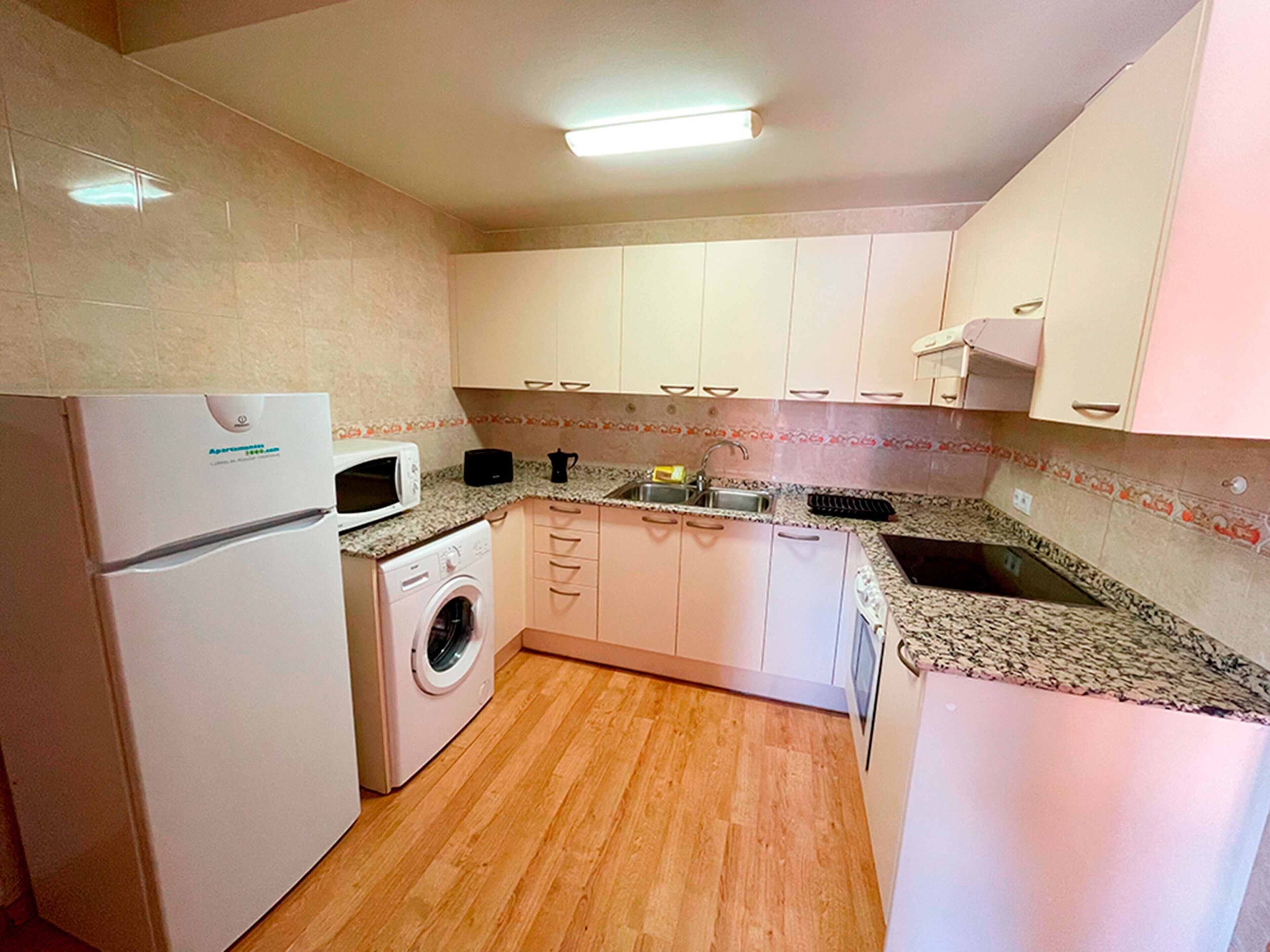 A compact kitchen with a washing machine, microwave, and sink.
