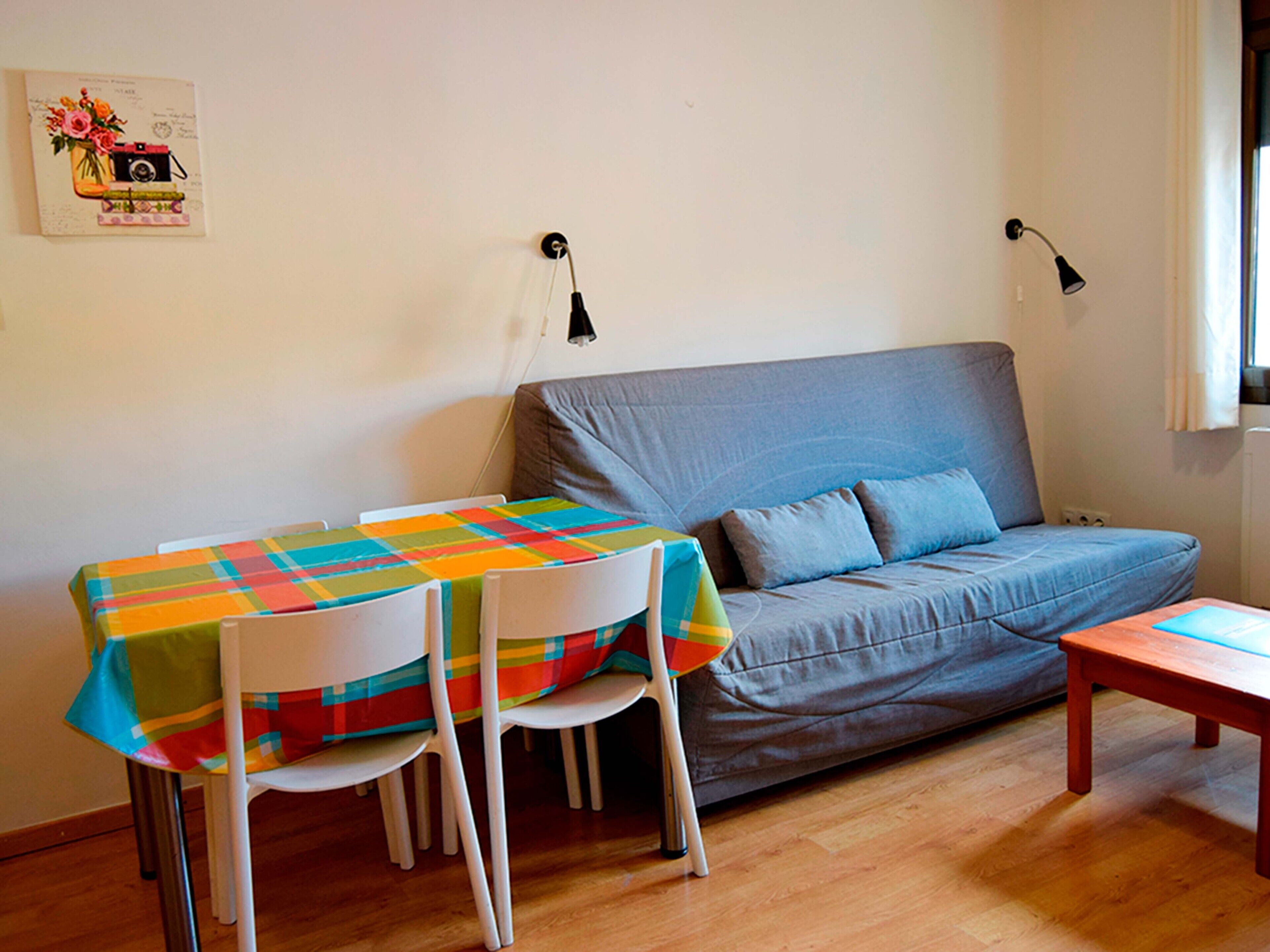 Een knus woongedeelte met een bank, een tafel en twee stoelen.