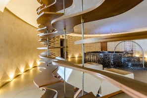 A modern interior with a spiral staircase, a seating area, and a decorative wall with a circular mosaic structure.