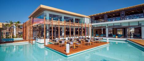 A modern hotel with a pool area, outdoor seating, and a view of the ocean.