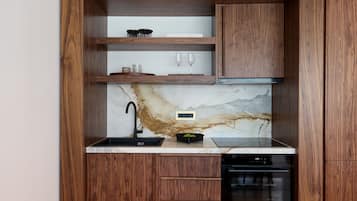 Una cocina con armarios de madera, salpicadero de mármol, un lavamanos negro y lavavajillas Bosch.