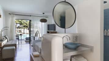 Un baño moderno con un espejo redondo grande, un lavabo azul y un banco de madera.