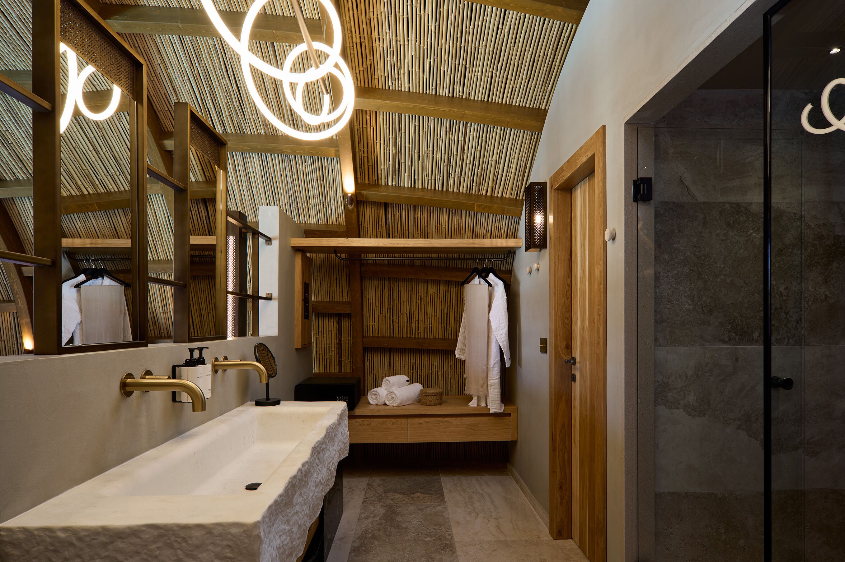 A modern bathroom with a large mirror, wooden shelves, and a glass shower enclosure.