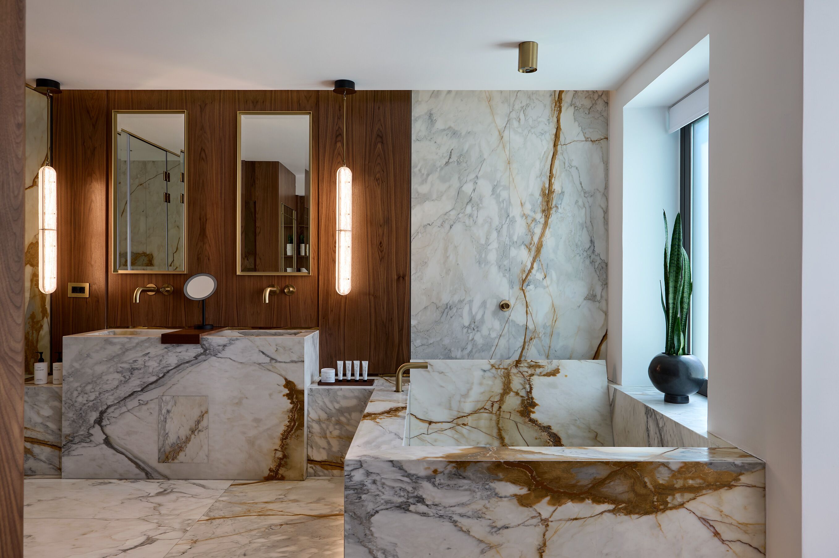 A modern bathroom with marble countertops, wooden cabinetry, and a large mirror.