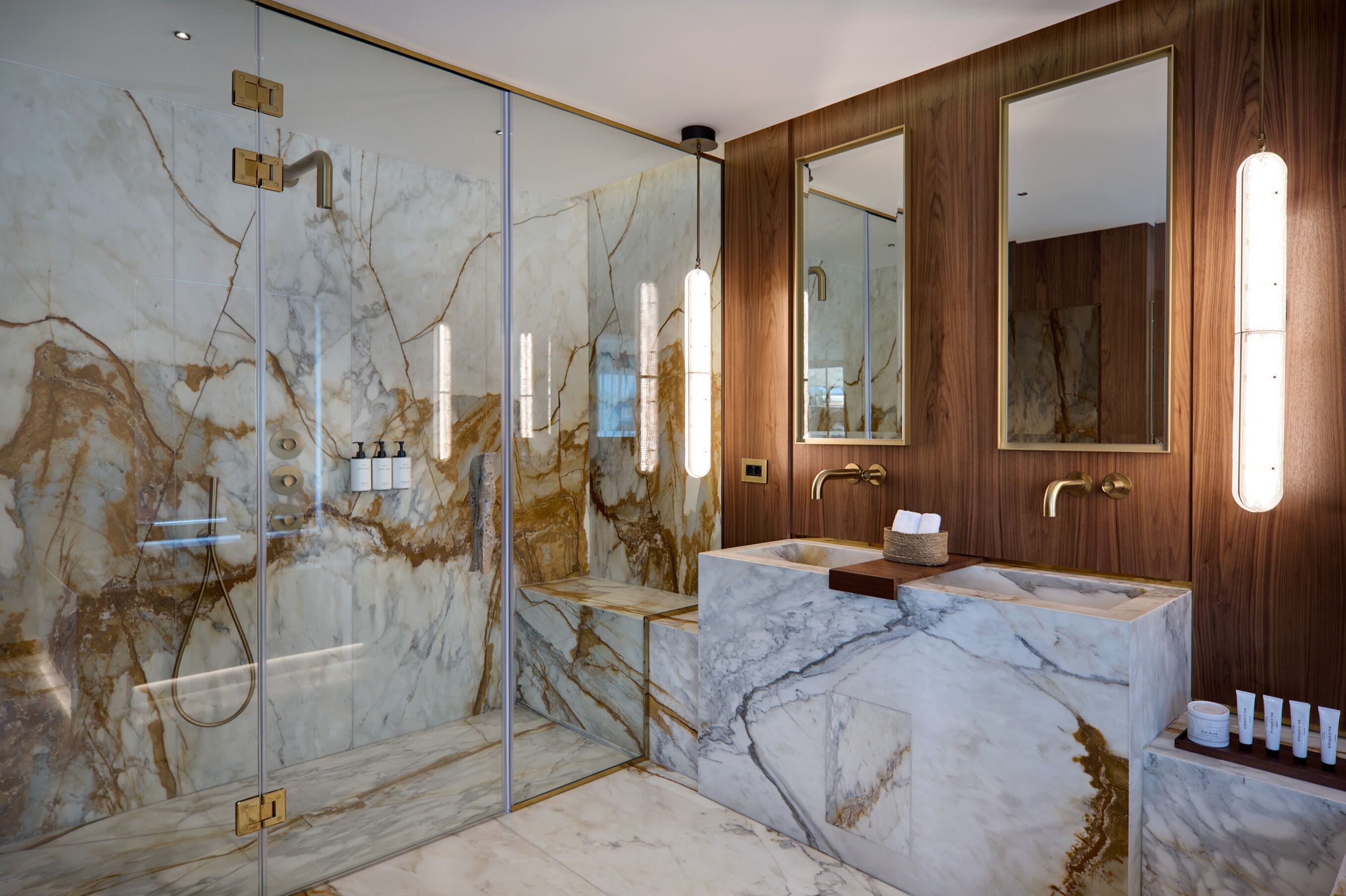A modern bathroom with a glass-enclosed shower, marble walls, and wooden paneling.