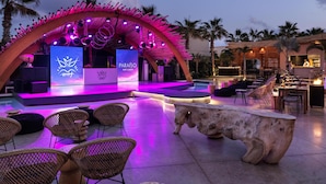 An outdoor lounge area with a stage, seating, and a pool.