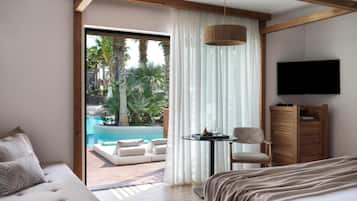 Une chambre d’hôtel dotée d’une grande fenêtre, d’un lit, d’un coin salon avec une table et d’un téléviseur.