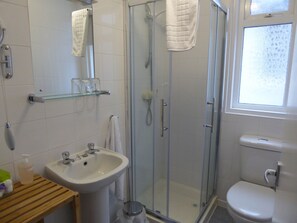 A bathroom with a glass-enclosed shower, a sink, and a toilet. - The Berwick - Over 40's Only (Blackpool)
