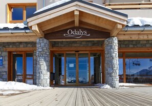 Entrada d'hotel amb façana de pedra, bigues de fusta i un rètol que diu "Odaly's".