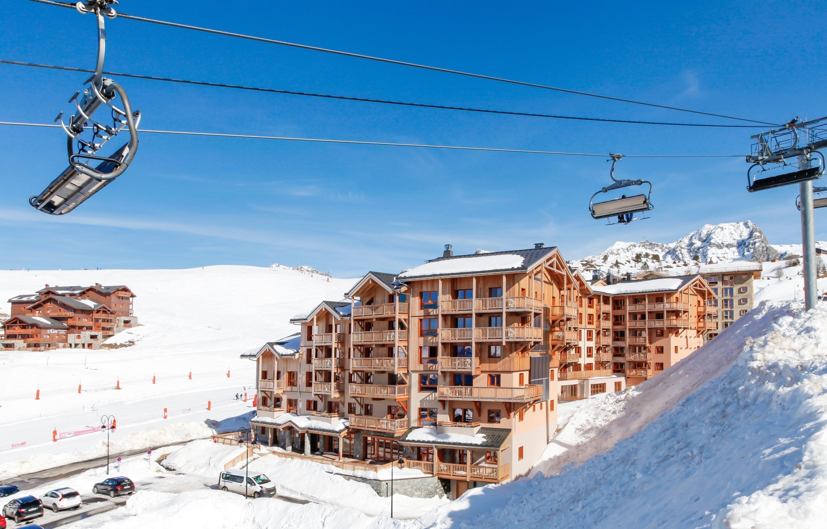 A multi-story hotel with balconies, ski lifts, and a snowy mountain backdrop.