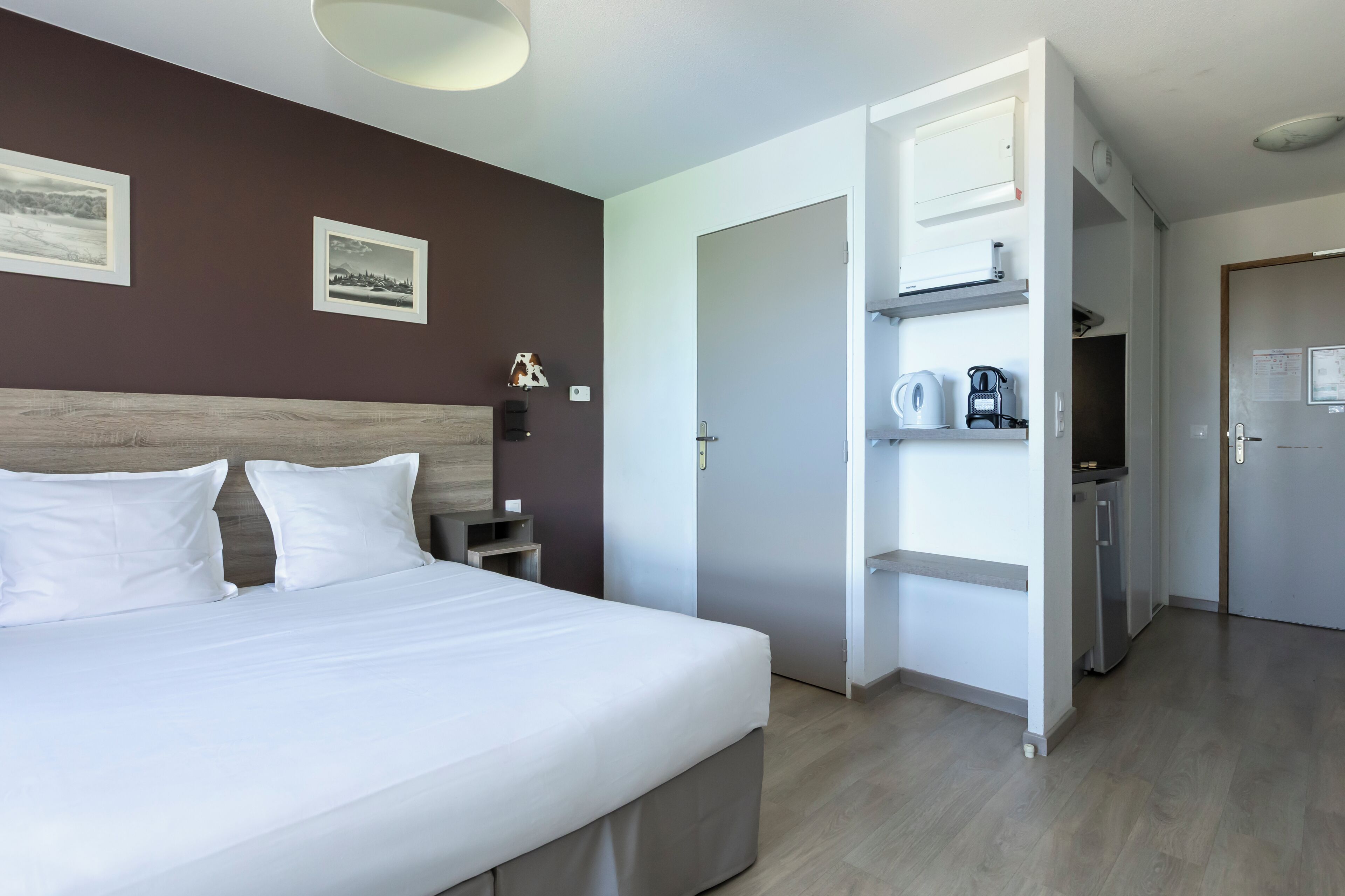 Una habitación de hotel con cama, armario, escritorio y kitchenette.