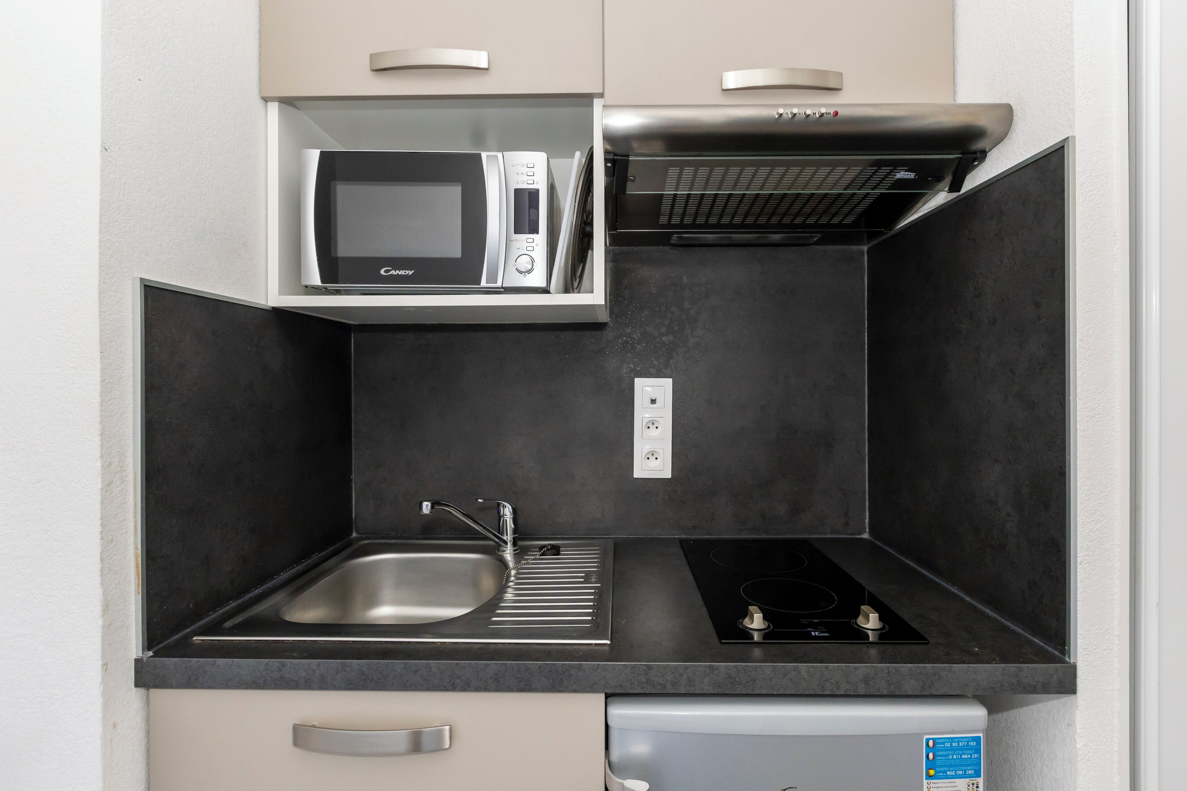 Une cuisine compacte équipée d’un four à micro-ondes, d’une cuisinière, d’un évier et d’un petit réfrigérateur.