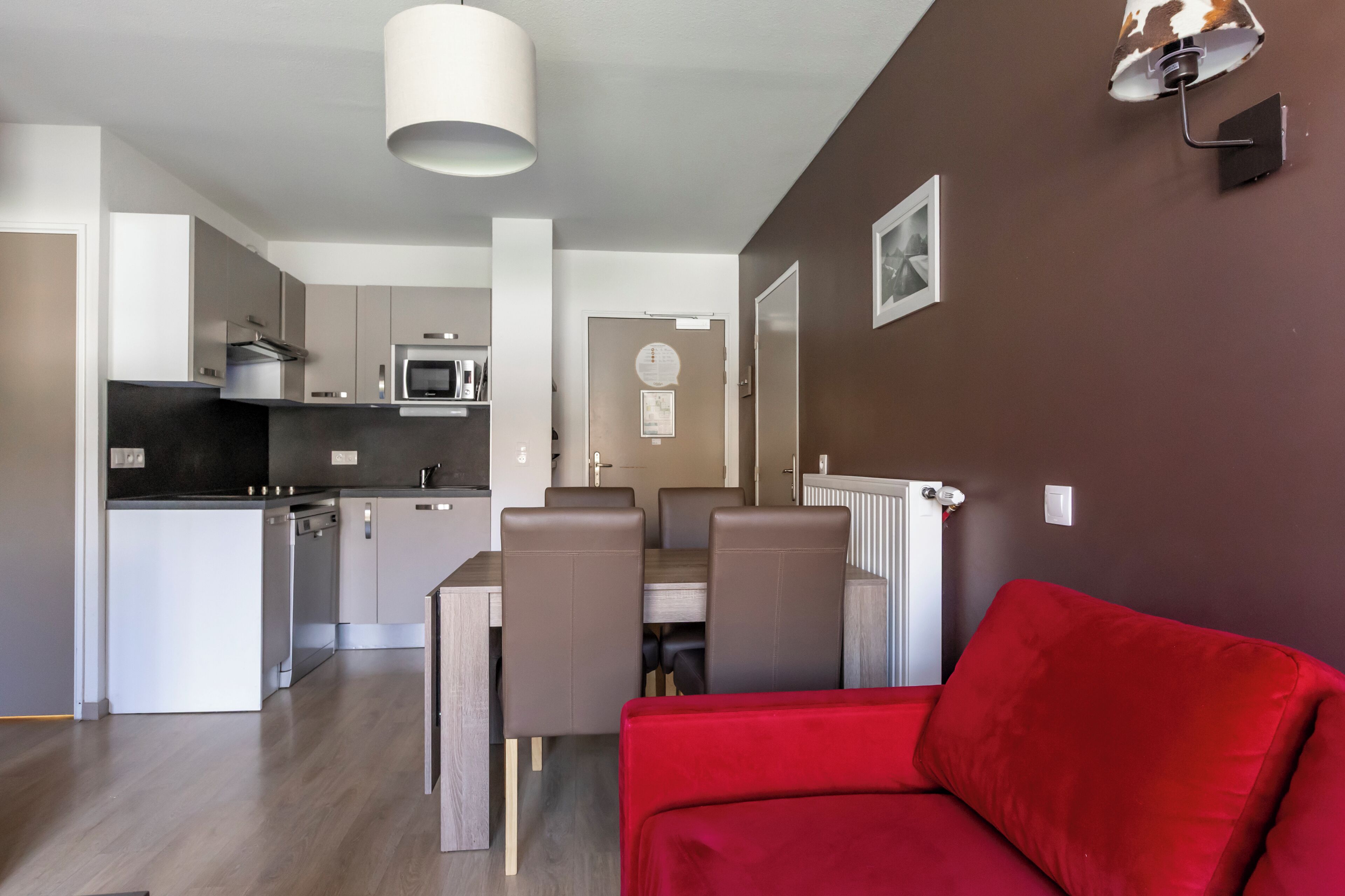 Eine moderne Küche mit Essbereich, einem roten Sofa und einer braunen Wand.