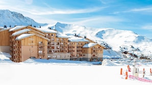 Un edificio de madera de varios pisos con balcones, rodeado de montañas nevadas.