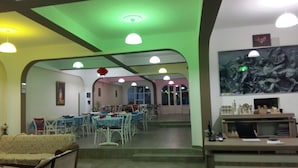 Un vestíbulo amplio con varias zonas de estar, incluyendo mesas y sillas, y un mostrador de recepción con ordenador y elementos decorativos.