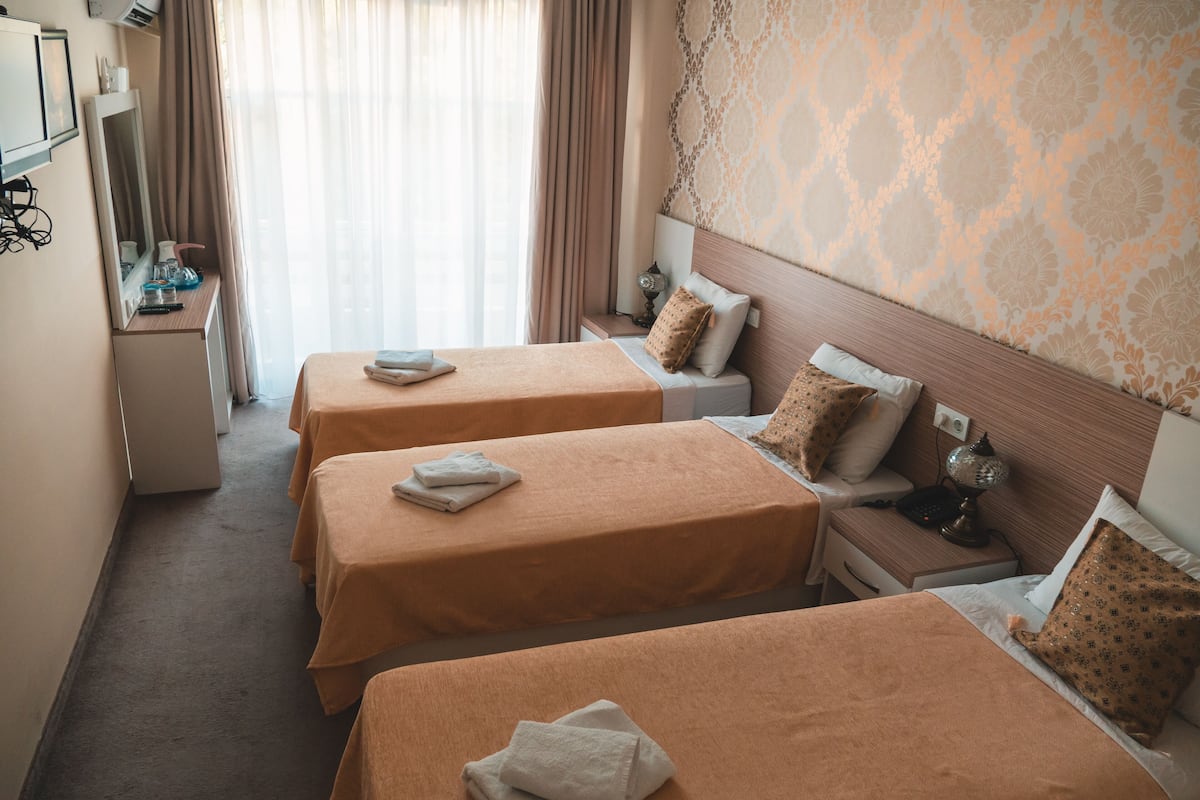 Habitación de hotel con dos camas, un escritorio, un espejo y un papel tapiz estampado.
