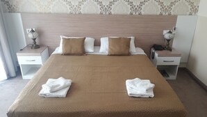 Una habitación de hotel con una cama grande, dos mesitas de noche, una lámpara de noche y un teléfono.