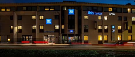 Un hotel con letreros que indican 'ibis budget', 'HOTEL' y 'HOTEL CLIMATISÉ'.