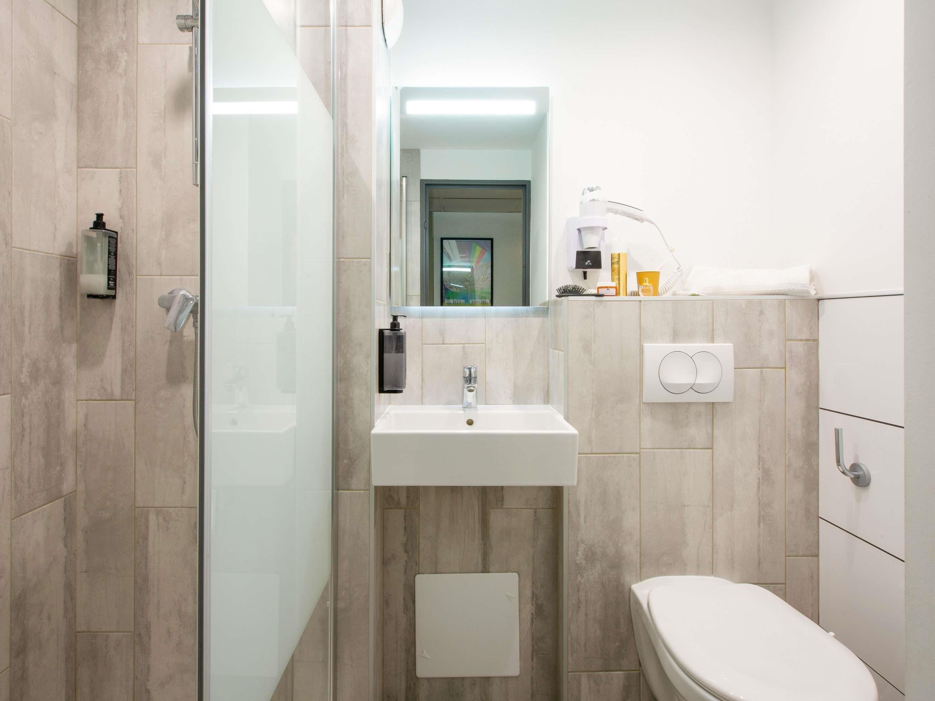A modern bathroom with a glass shower enclosure, a white sink, and a toilet.
