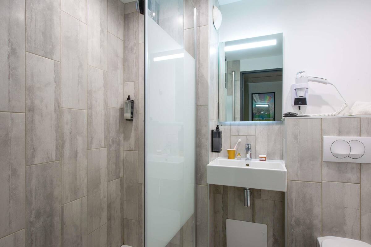 A modern bathroom with a glass shower enclosure, a sink with a mirror, and a toilet.