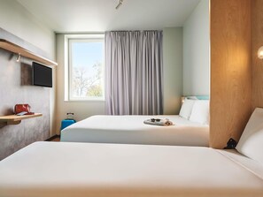 A hotel room with two beds, a TV mounted on the wall, a window with curtains, and a wooden panel on one side. - ibis budget Mulhouse Centre Gare (Mulhouse)