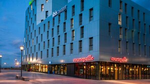 Moderni hotelli, jossa on tasainen julkisivu, useita ikkunoita ja kaksi Courtepaille-ravintolan kylttiä.